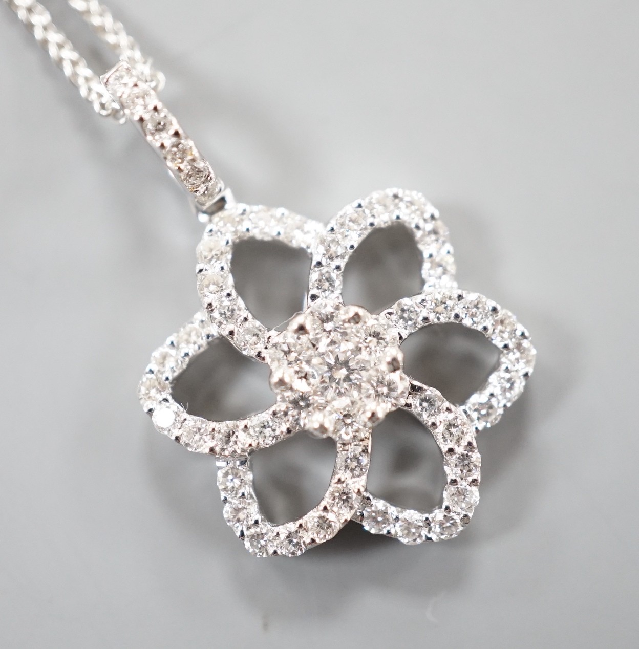 A modern 750 white metal and diamond chip set openwork flower head cluster pendant, overall 24mm, on an 18ct white gold fine link chain, 40cm, gross weight 4.9 grams